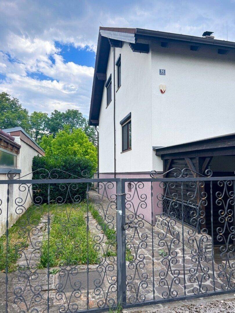 Seitenansicht des Hauses mit einem Weg, der zum hinteren Bereich führt, und einem dekorativen Tor.