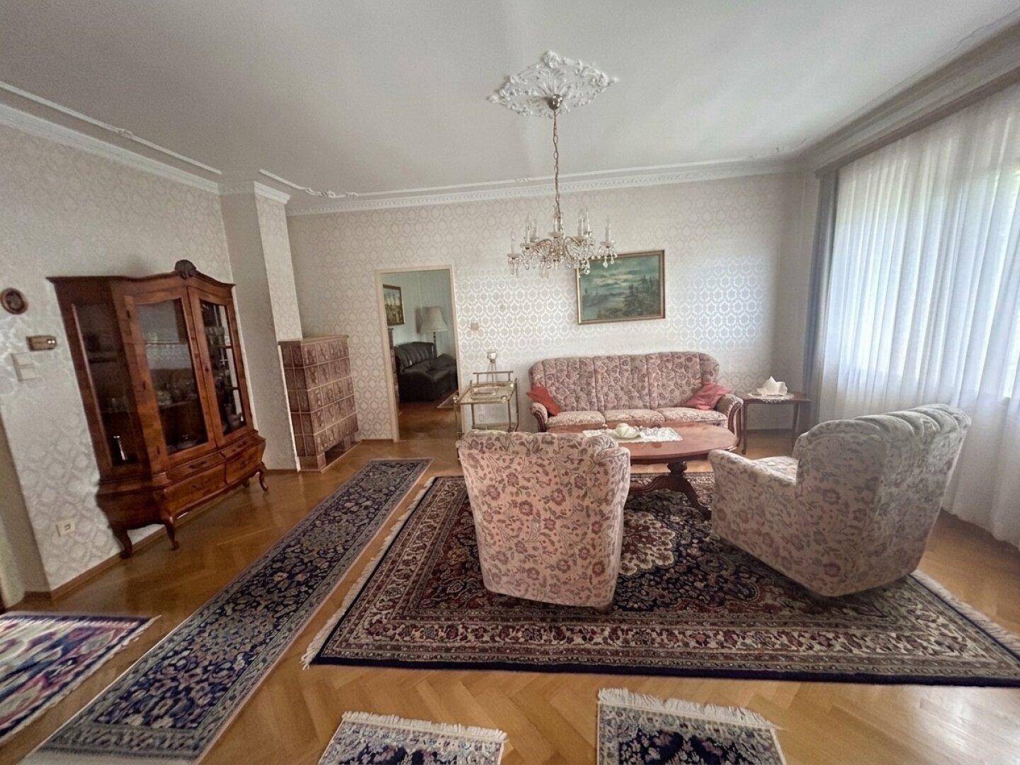 Gemütliches Wohnzimmer mit traditionellen Möbeln, Parkettboden und einem Kachelofen.