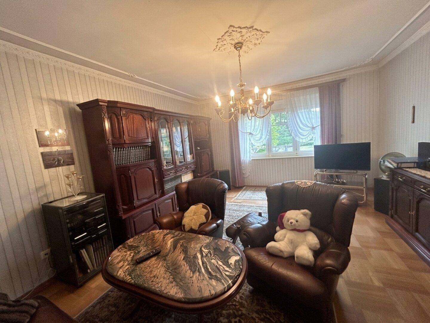 Wohnzimmer mit dunklen Holzmöbeln, Ledersesseln und einem gemütlichen Ambiente.