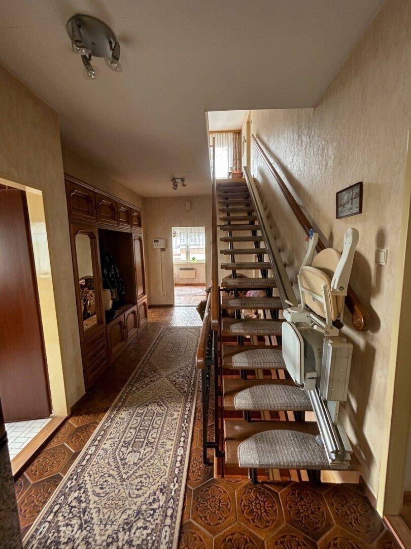 Geräumiger Flur mit Treppe und einem Treppenlift für barrierefreien Zugang zu den oberen Etagen.