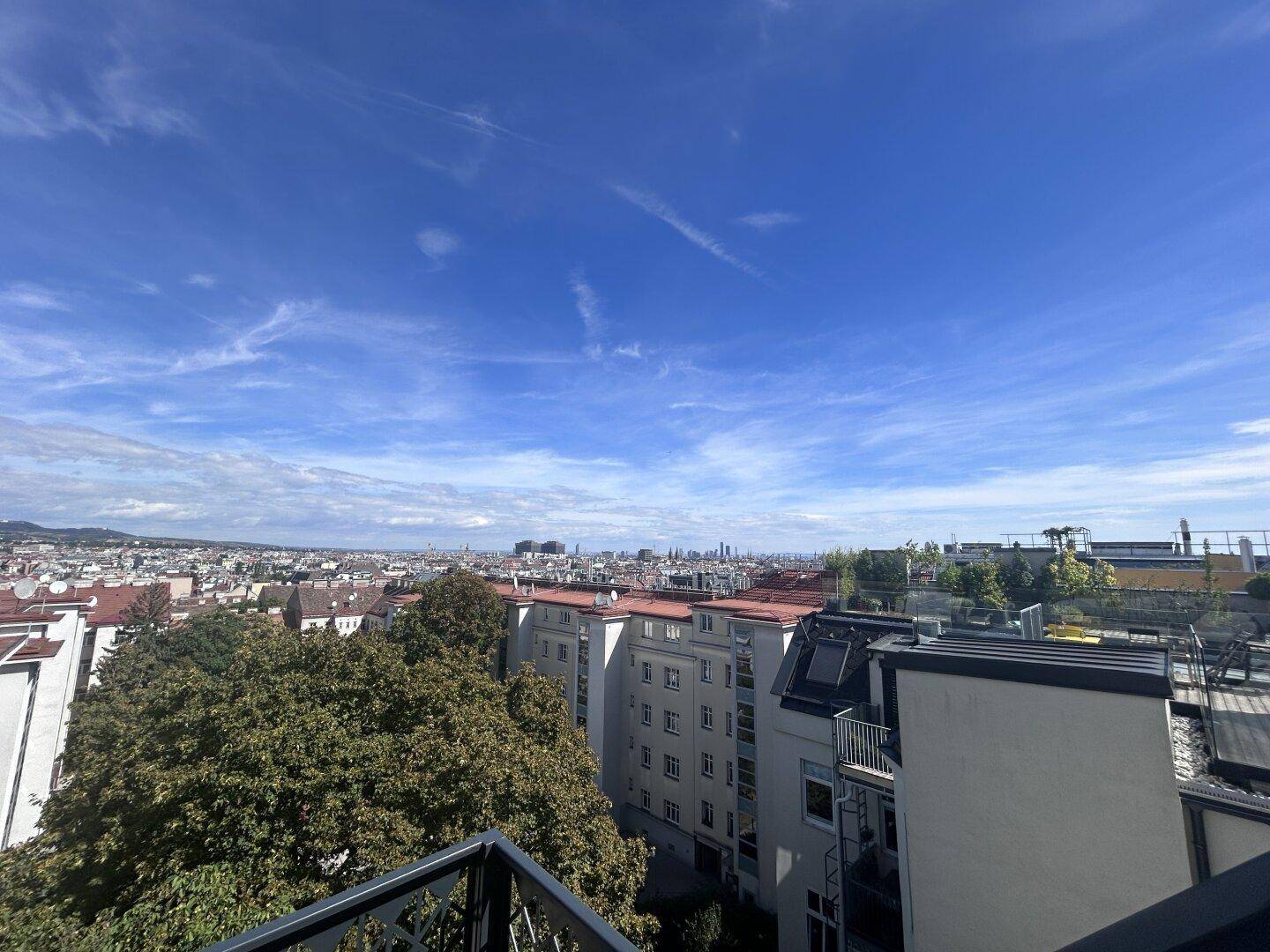 Panoramablick über die städtische Umgebung mit Wohngebäuden und üppigem Grün unter blauem Himmel.