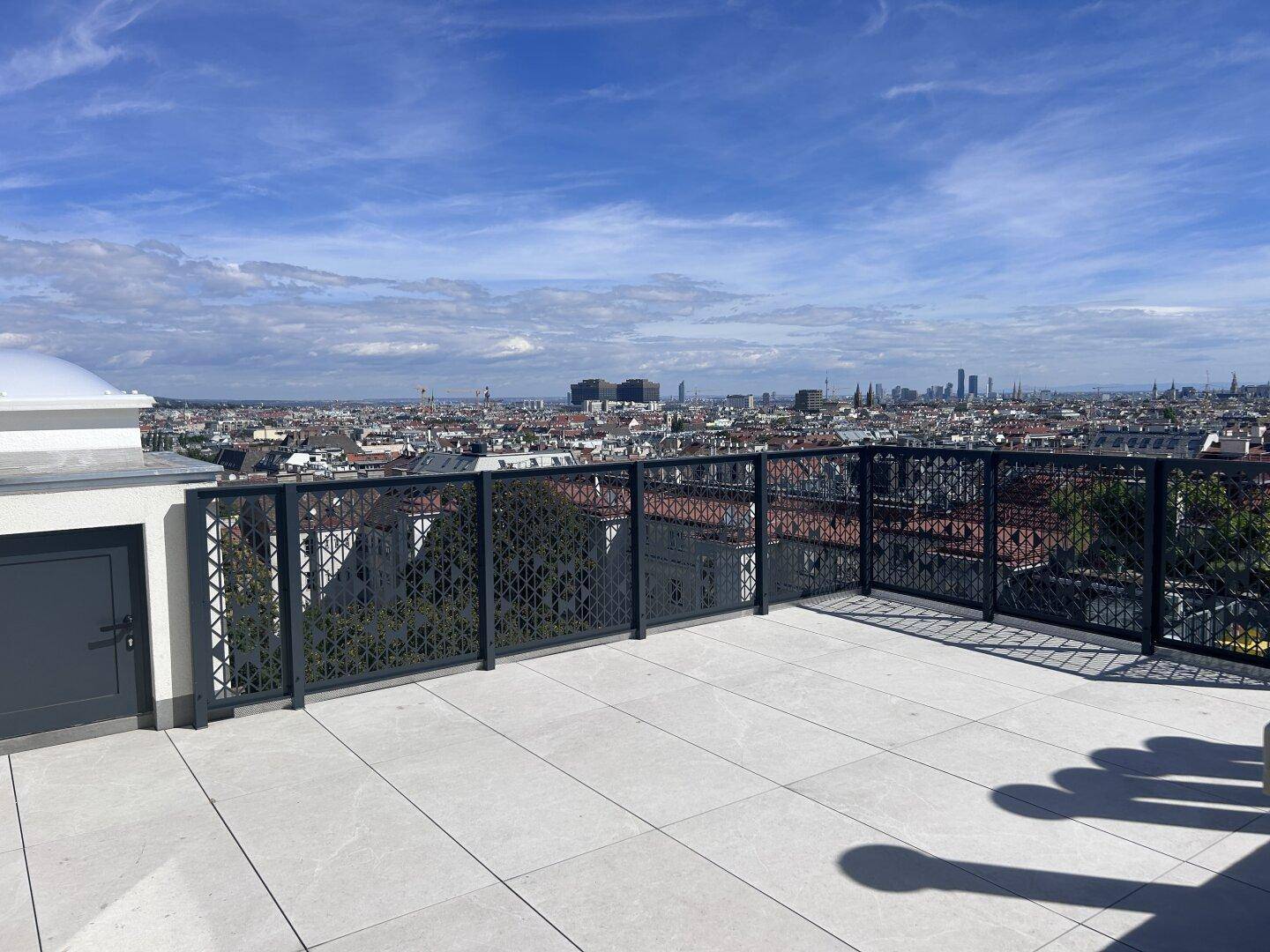 Weitläufige Dachterrasse mit hellen Fliesen und beeindruckendem Ausblick auf die urbane Landschaft.