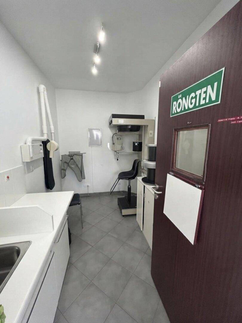 Röntgenraum mit spezieller Ausrüstung, Waschbecken und einer Tür mit "Röntgen"-Beschriftung.
