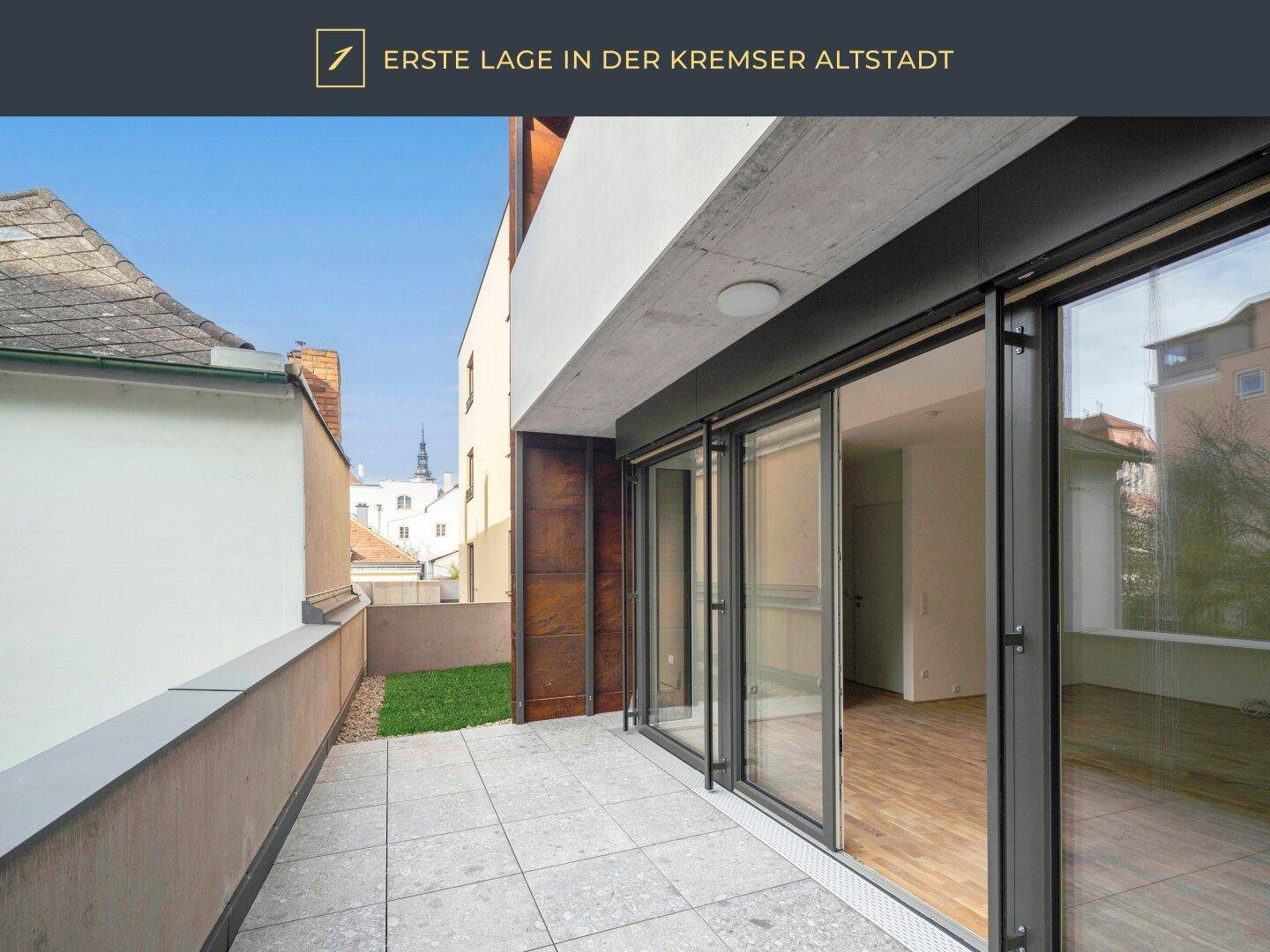 Geräumige Terrasse mit Fliesenboden und großen Glasschiebetüren, die in den Wohnbereich führen.
