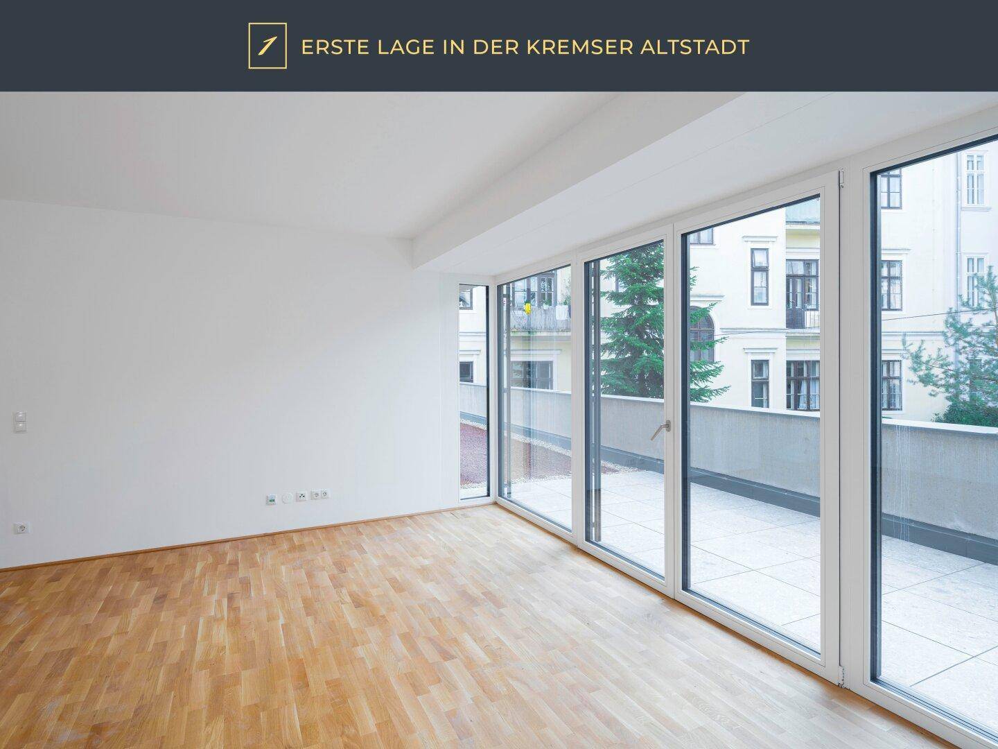 Heller Wohnraum mit Parkettboden und großen Fenstern, die Zugang zu einer Terrasse bieten.