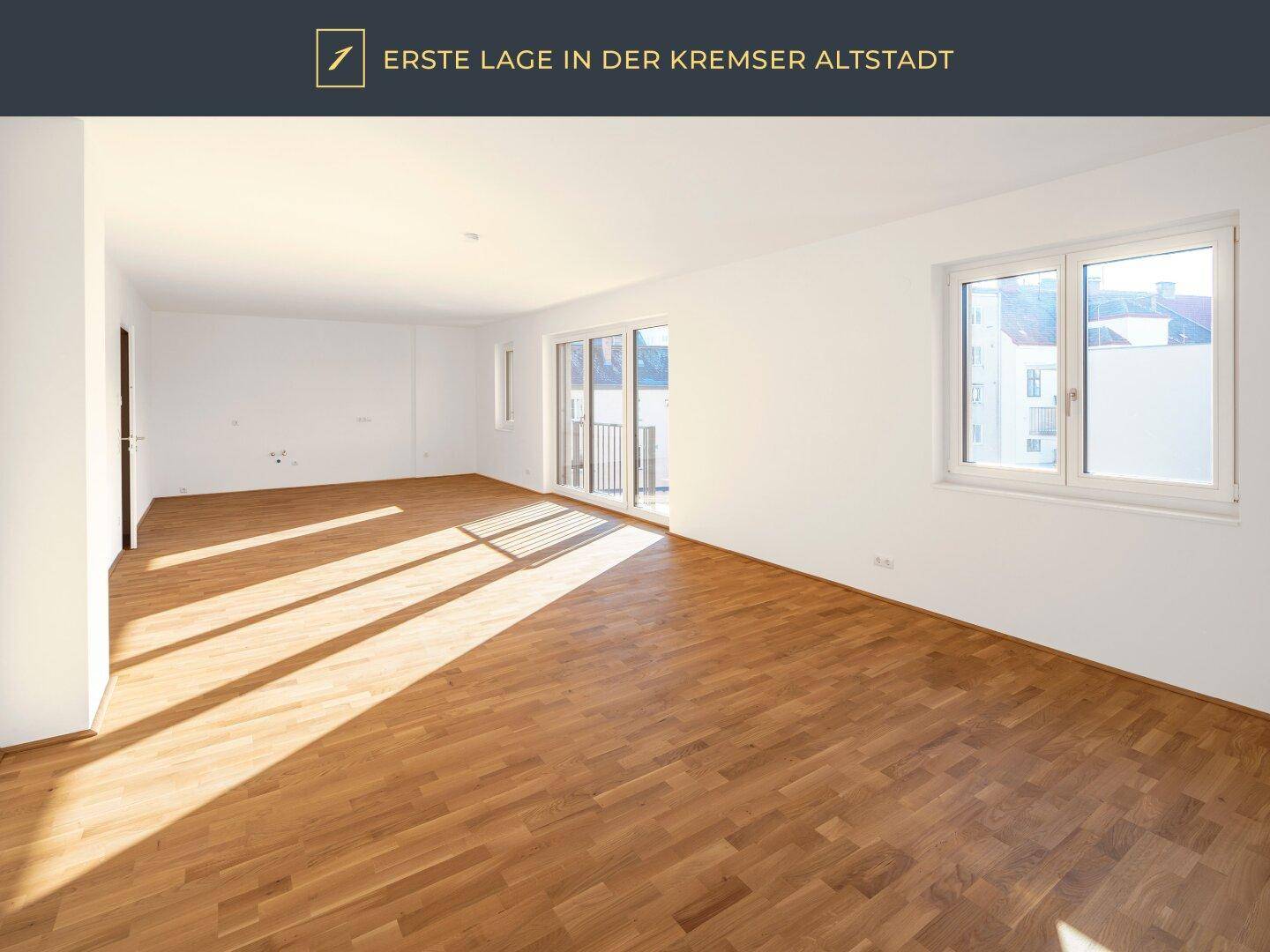 Helles, leeres Zimmer mit Parkettboden und Zugang zu einem französischen Balkon.