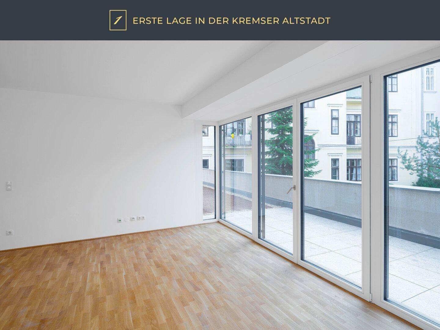 Helles Zimmer mit Parkettboden und bodentiefen Fenstern, die auf eine Terrasse führen.