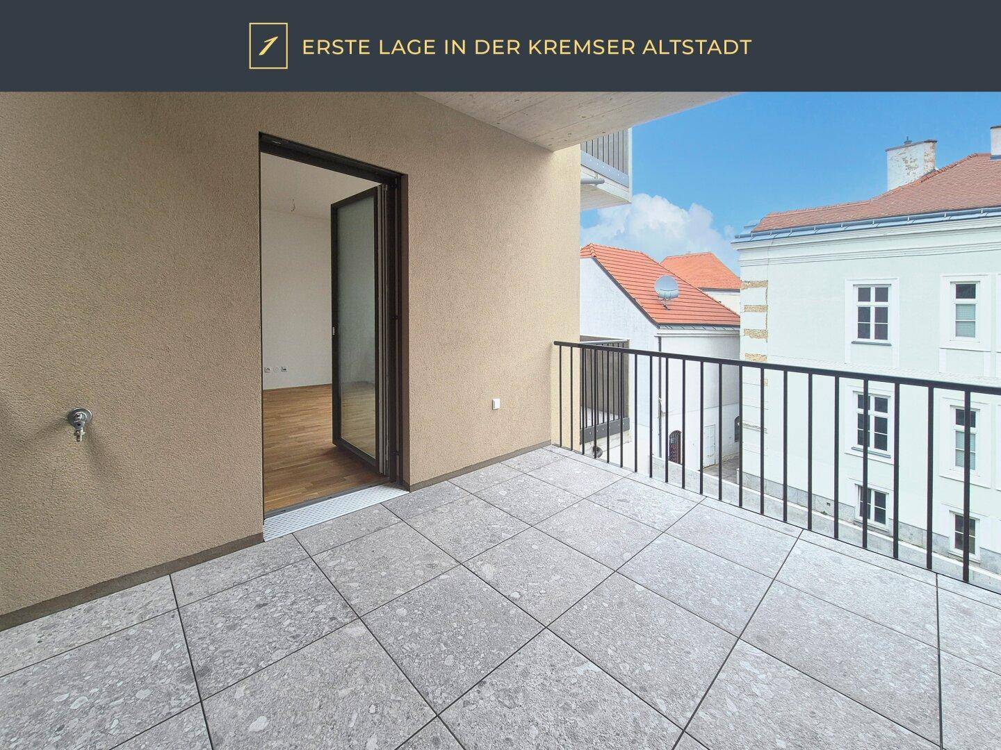 Sonniger Balkon mit Fliesenboden und Blick auf die Dächer der Altstadt.