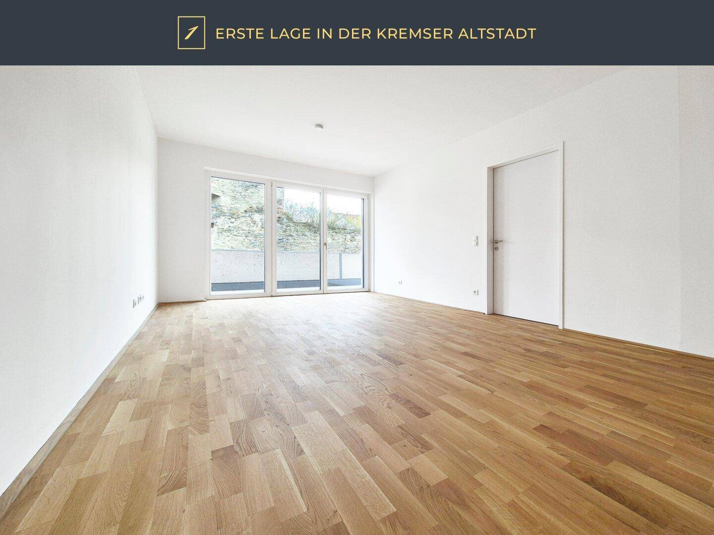 Helles Zimmer mit Parkettboden und großen Fenstern, die auf eine Terrasse führen.