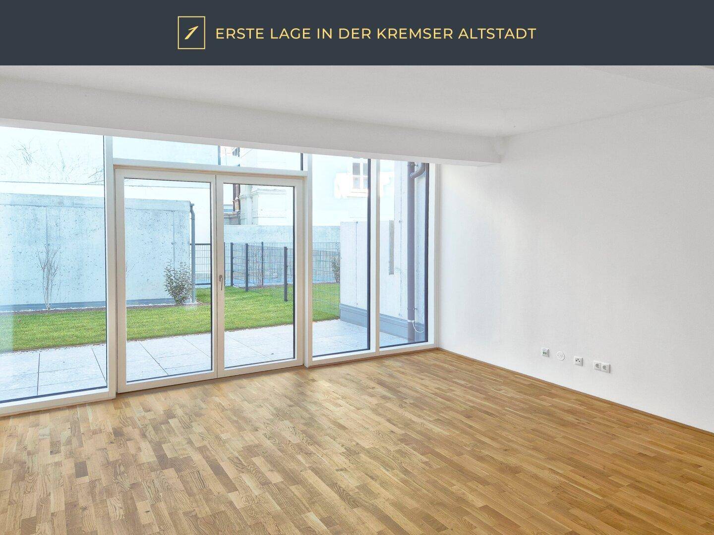 Helles Zimmer mit Parkettboden und großen Fenstern, die auf eine Terrasse führen.