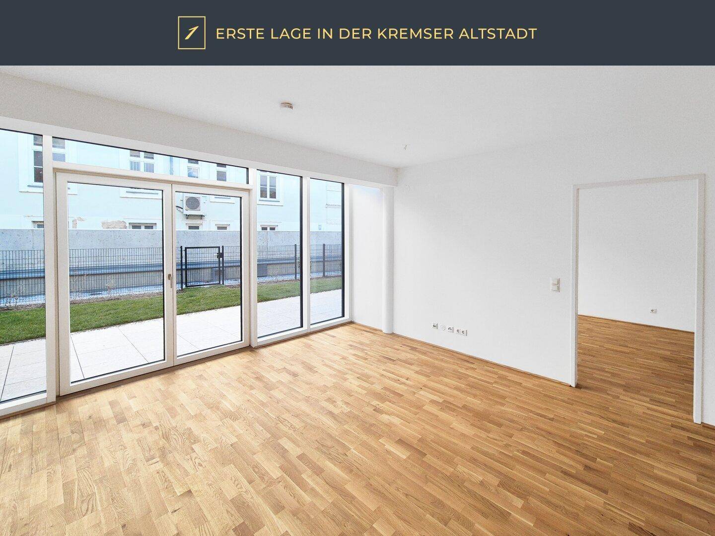 Helles Zimmer mit Parkettboden und großen Fenstern, die auf eine Terrasse führen.