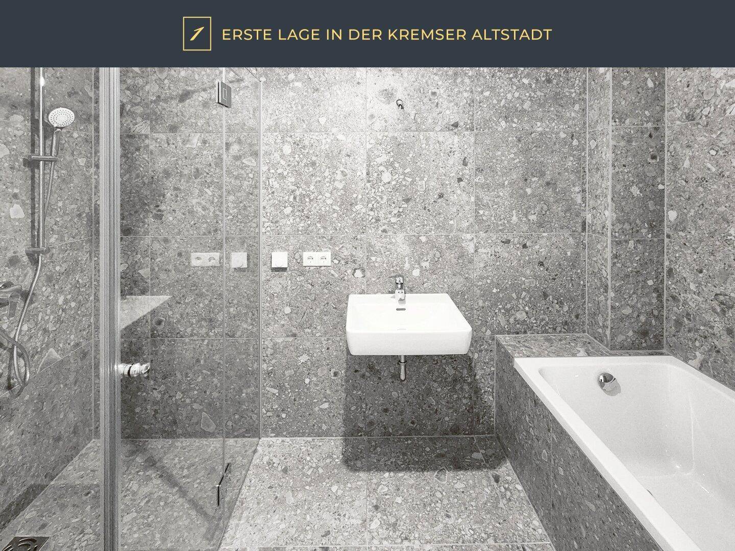 Modernes Badezimmer mit grauen Feinsteinzeugplatten, Dusche und Badewanne.
