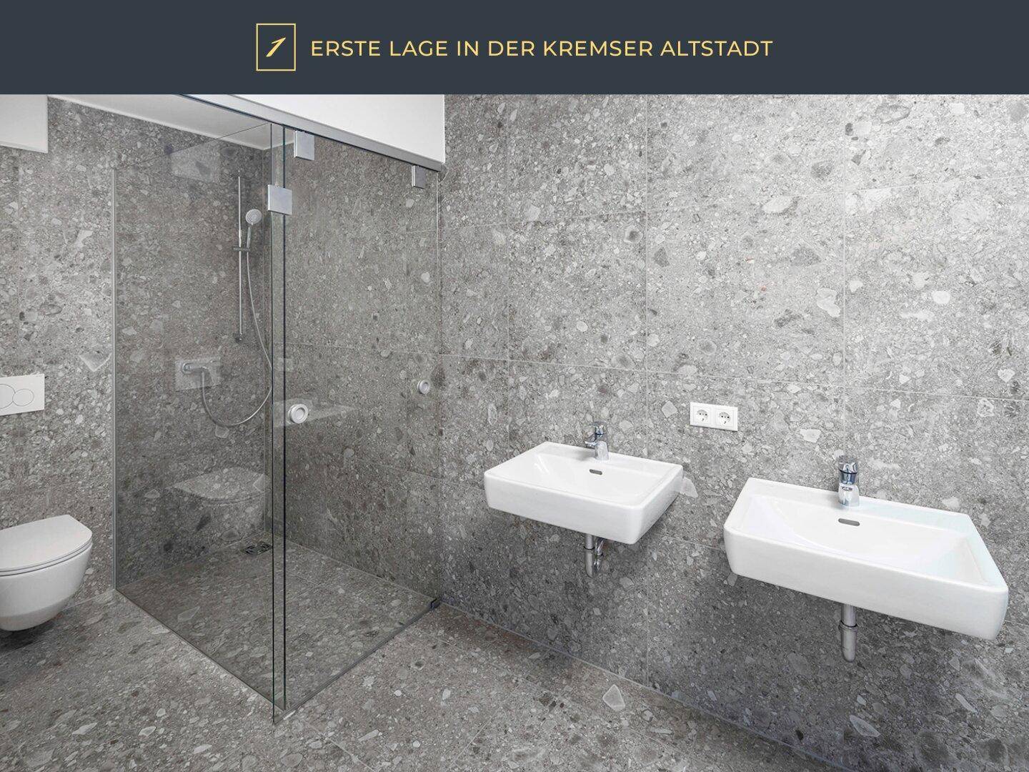 Modernes Badezimmer mit grauen Feinsteinzeugplatten, großer Dusche und Doppelwaschbecken.