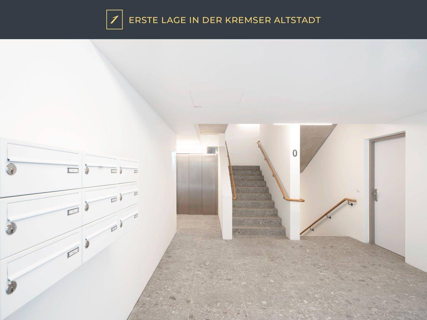 Heller Eingangsbereich mit Briefkästen, Treppe und Aufzug.