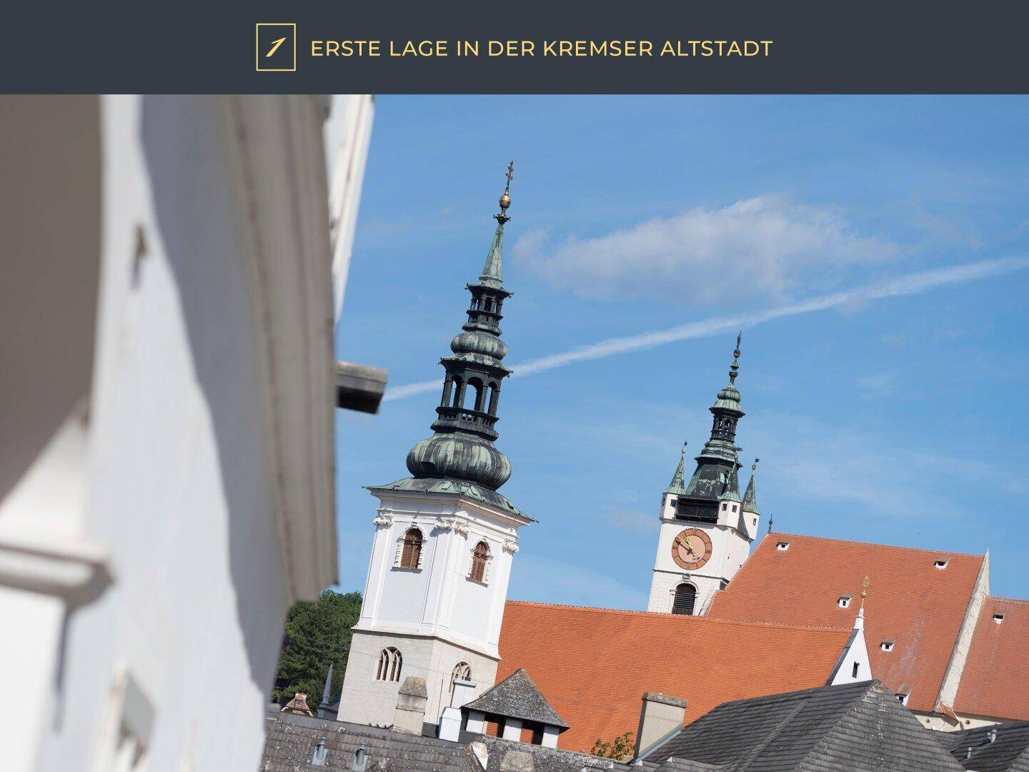 Historische Kirchtürme in der Altstadt von Krems unter blauem Himmel.