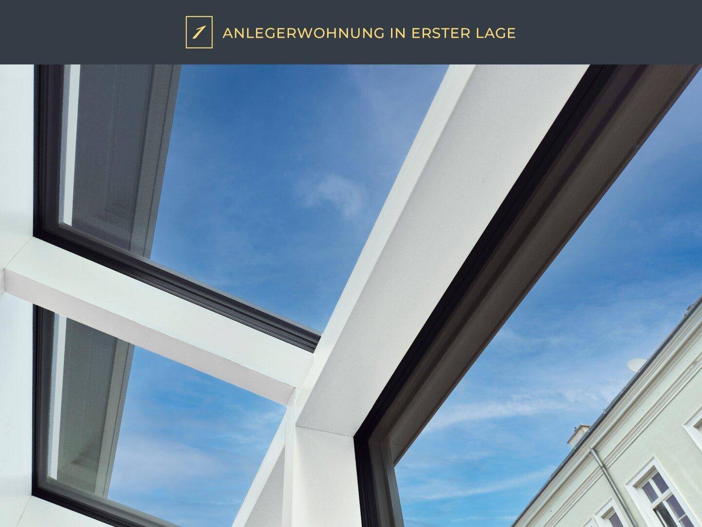 Detailaufnahme eines modernen Fensterrahmens mit Blick auf den blauen Himmel und ein Nachbargebäude.