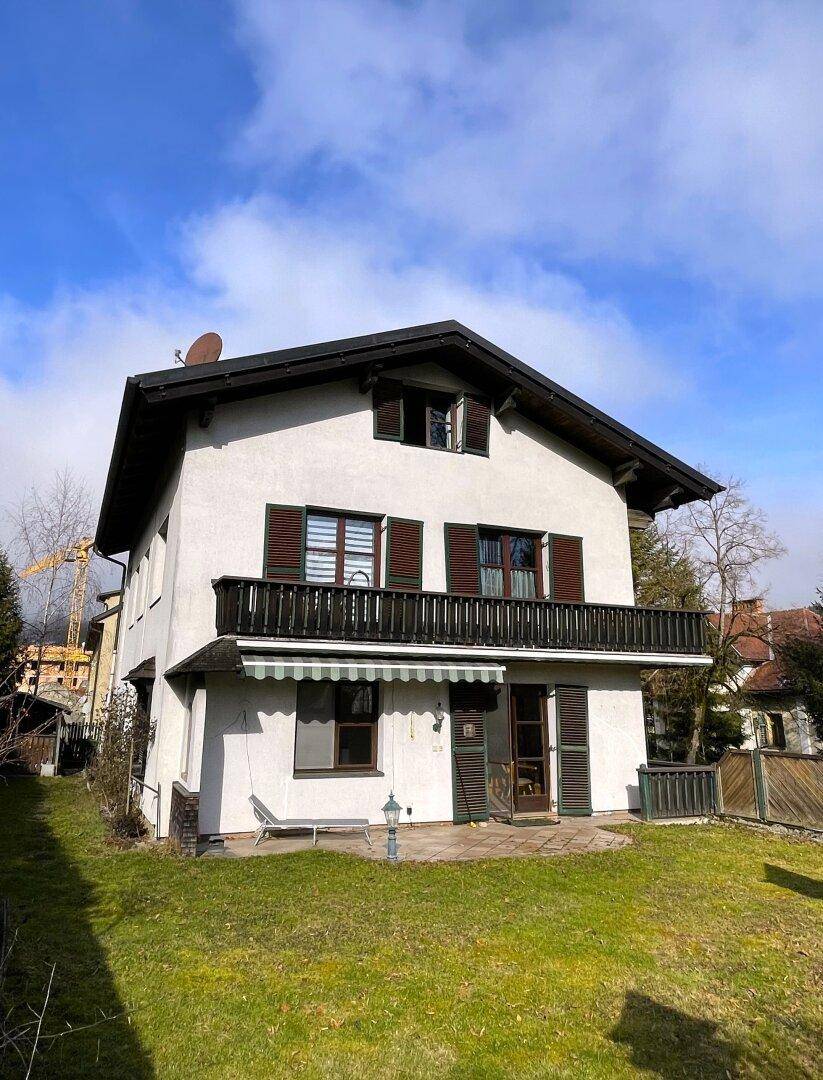 Rückseite des Hauses mit Rasenfläche, Terrasse und Balkon im Obergeschoss.