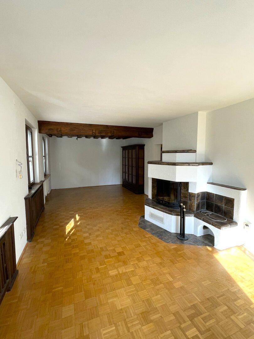 Großzügiges Wohnzimmer mit Kamin, Parkettboden und Holzbalken.