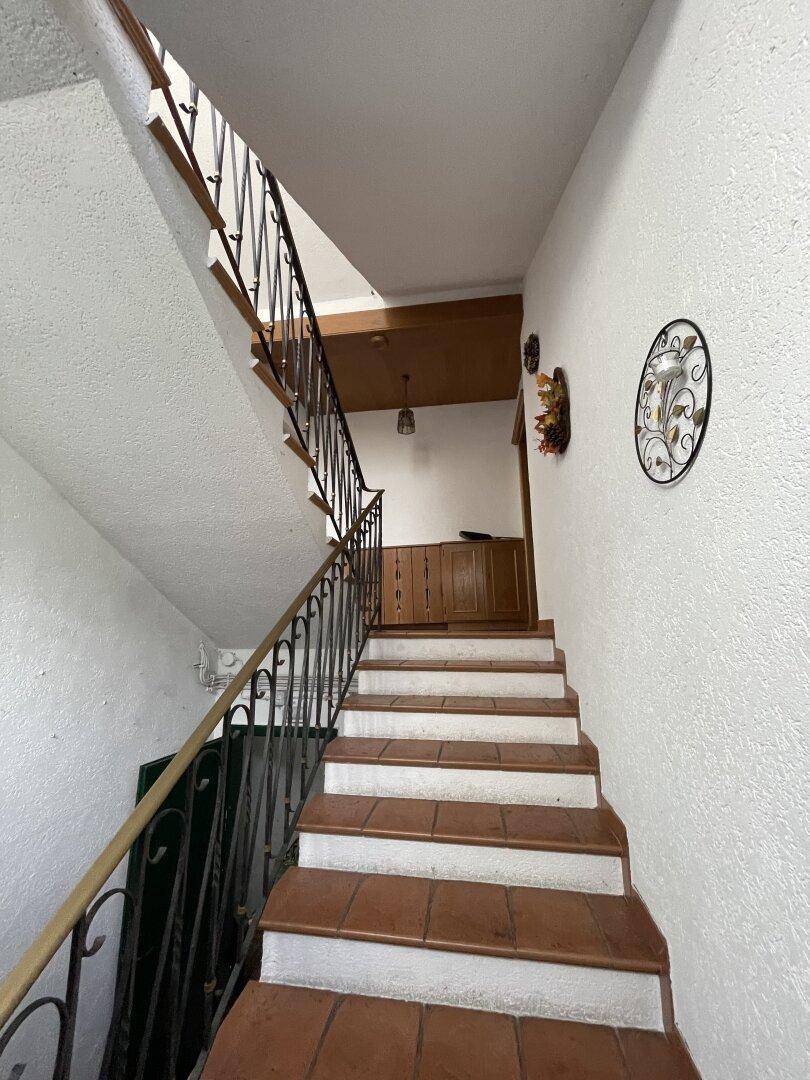 Treppenaufgang mit Terrakottafliesen und schlichtem Geländer.