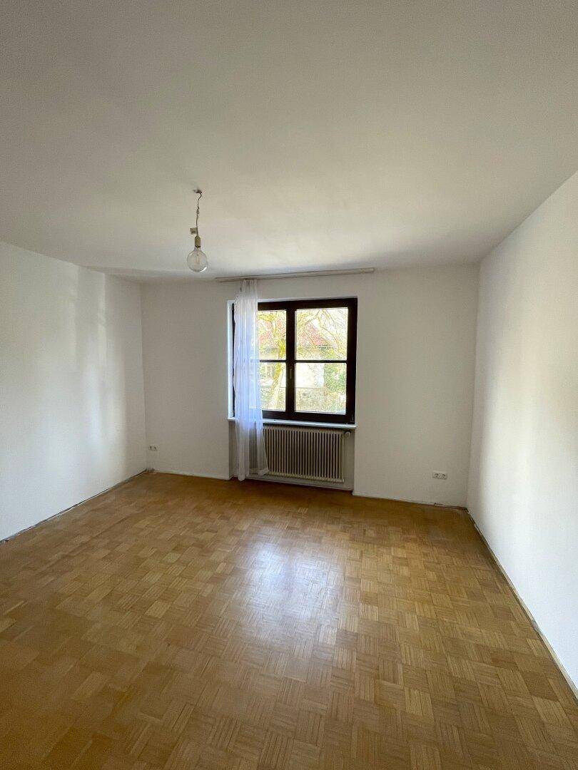 Helles Schlafzimmer mit Parkettboden und großem Fenster.