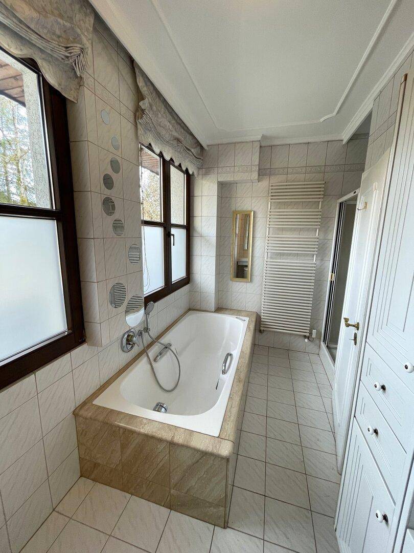 Badezimmer mit Badewanne, Fliesen und Fenster für Tageslicht.