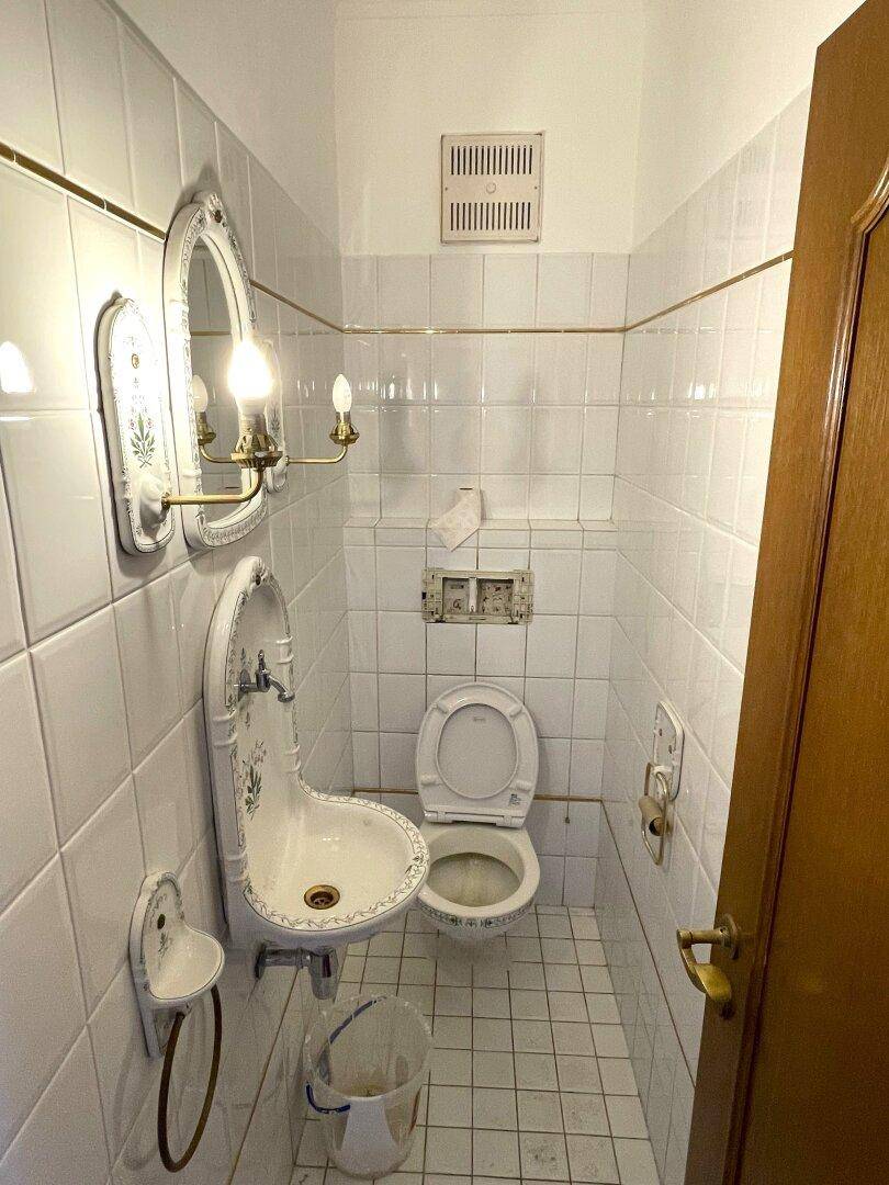 Kleines Gäste-WC mit traditionellem Waschbecken und Fliesen.