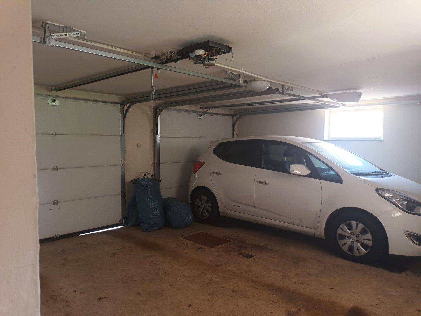 Geräumige Garage mit automatischem Toröffner und Platz für ein Fahrzeug.