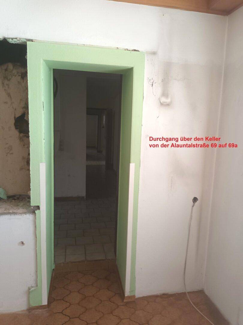 Durchgang im Kellerbereich mit grünem Türrahmen, der zwei Gebäudeteile verbindet.