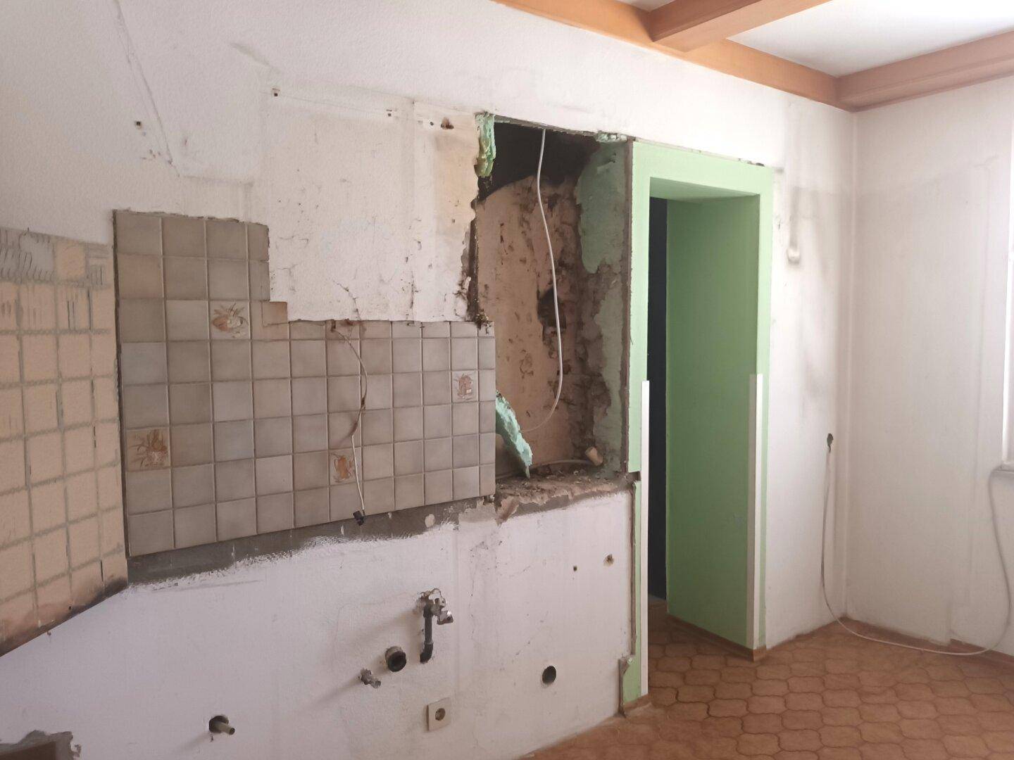 Küche im Umbau mit entfernten Schränken und freigelegter Wand.