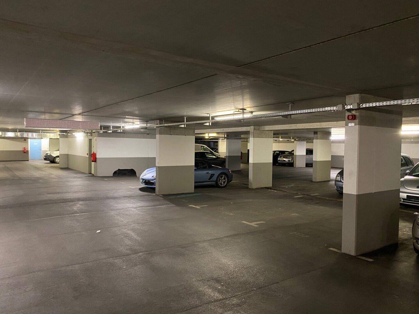Geräumige Tiefgarage mit vielen Stellplätzen, Betonpfeilern und Beleuchtung.