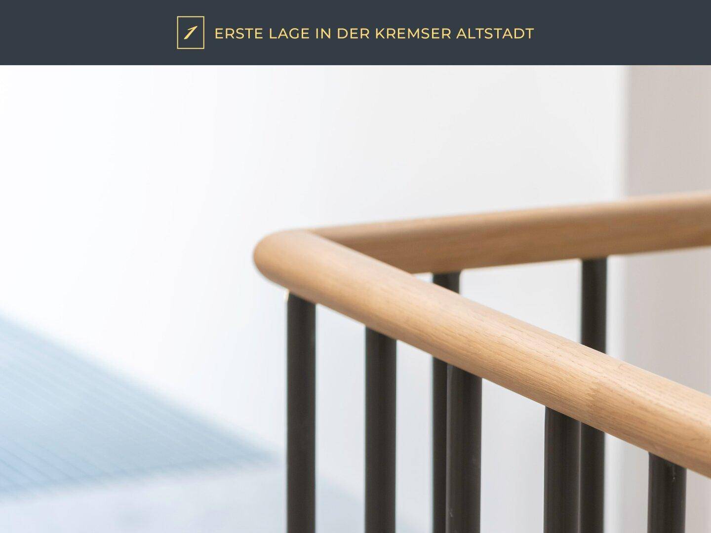 Detailansicht eines Holzhandlaufs an einer modernen Treppe mit schwarzen Geländerstäben.