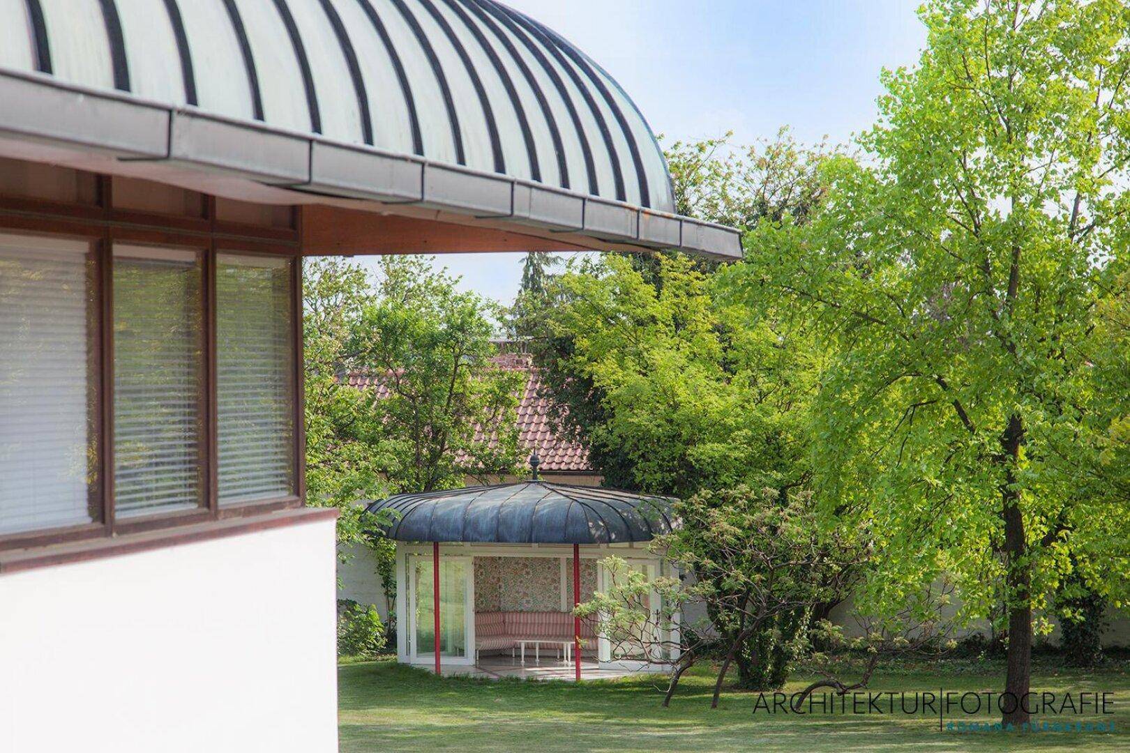 Blick auf einen eleganten Gartenpavillon mit Kuppeldach und umliegender grüner Landschaft.