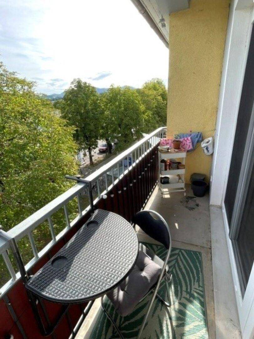 Kleiner Balkon mit Sitzgelegenheiten, umgeben von Bäumen und mit Blick auf die umliegende Landschaft.