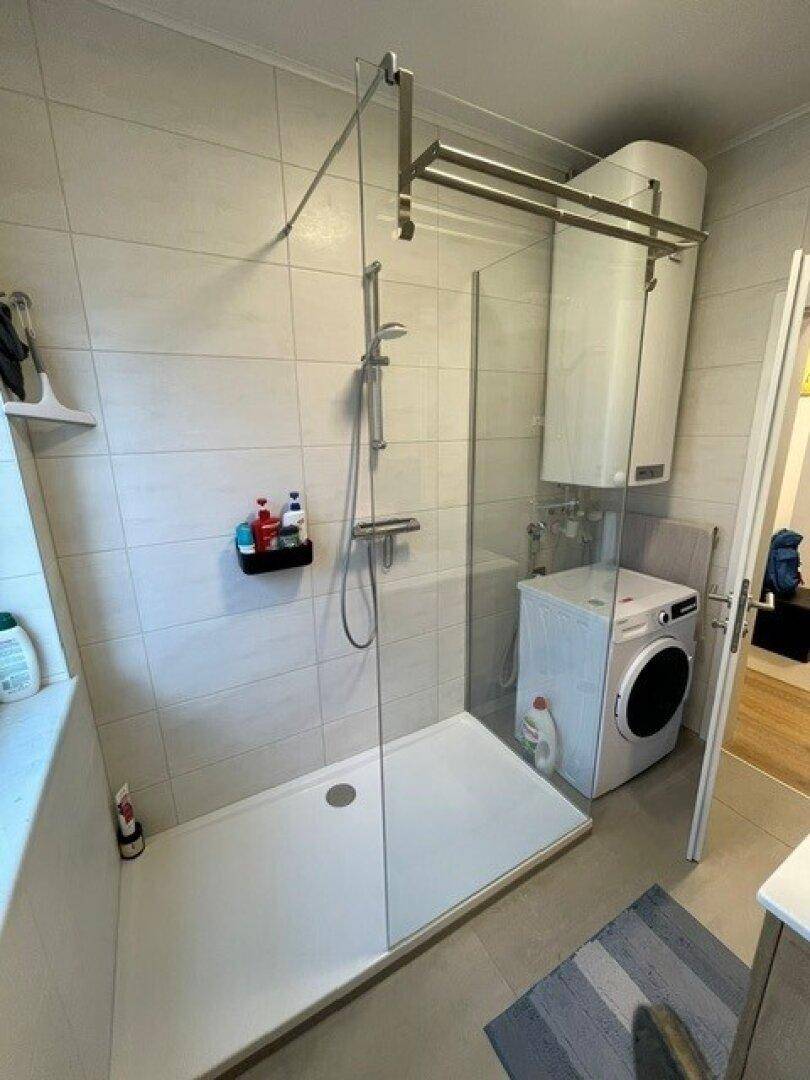 Funktionales Badezimmer mit ebenerdiger Dusche, Waschmaschine und Warmwasserbereiter.
