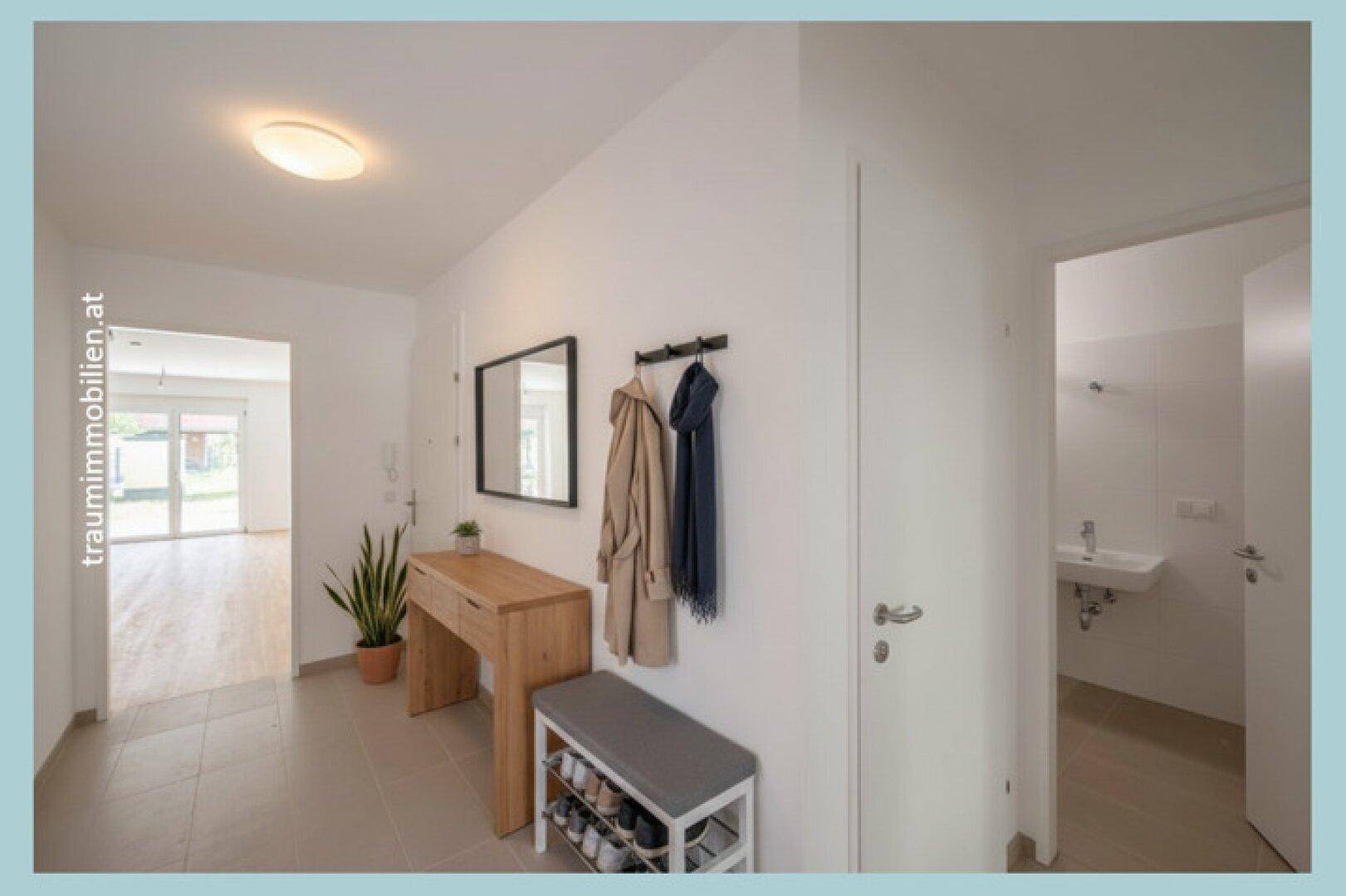Heller Eingangsbereich mit Garderobe, Spiegel und praktischer Schuhablage.