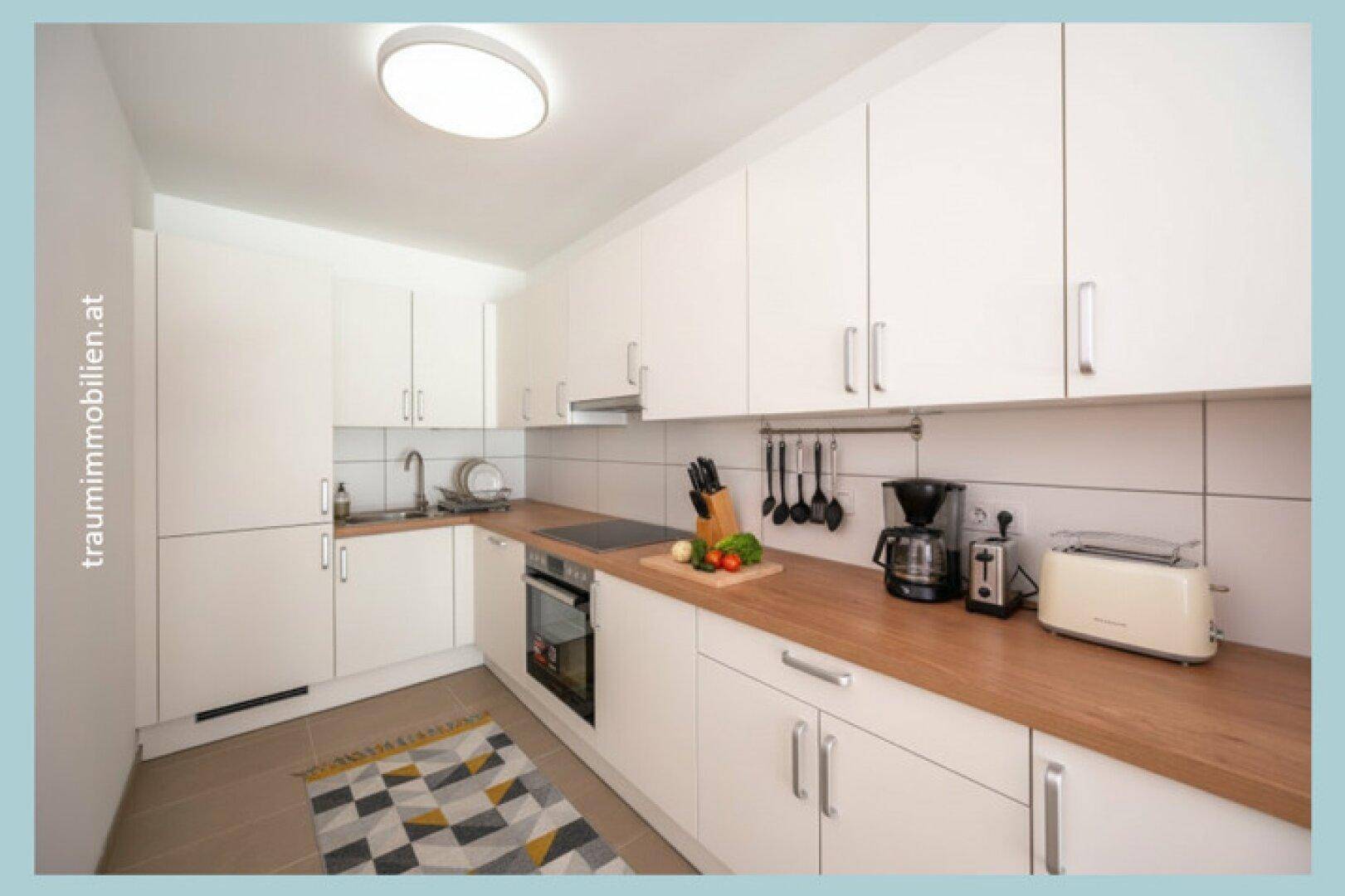 Moderne Küche mit weißen Schränken, Holz-Arbeitsplatten und neuen Geräten.