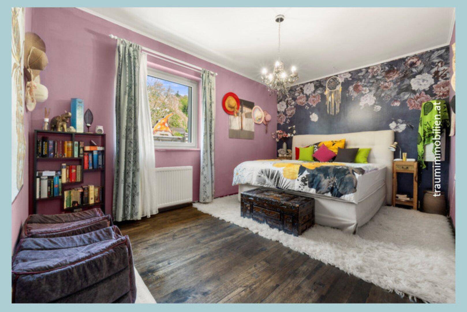 Gemütliches Schlafzimmer mit lila Wänden, floraler Akzenttapete und dunklem Holzboden.