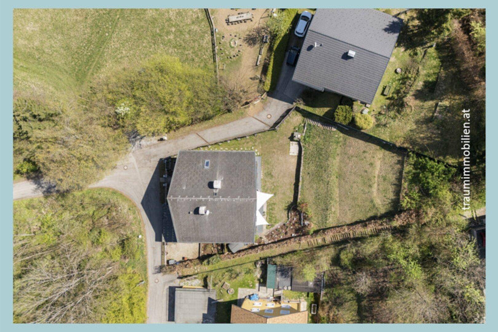 Luftaufnahme des Hauses mit Garten, Carport und umliegenden Grundstücken.