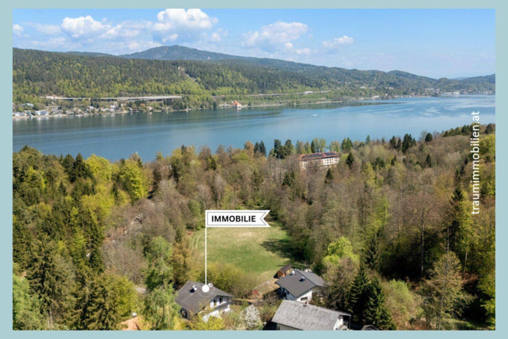 Luftaufnahme der Immobilie in grüner Umgebung mit Blick auf den Wörthersee und die Berge.