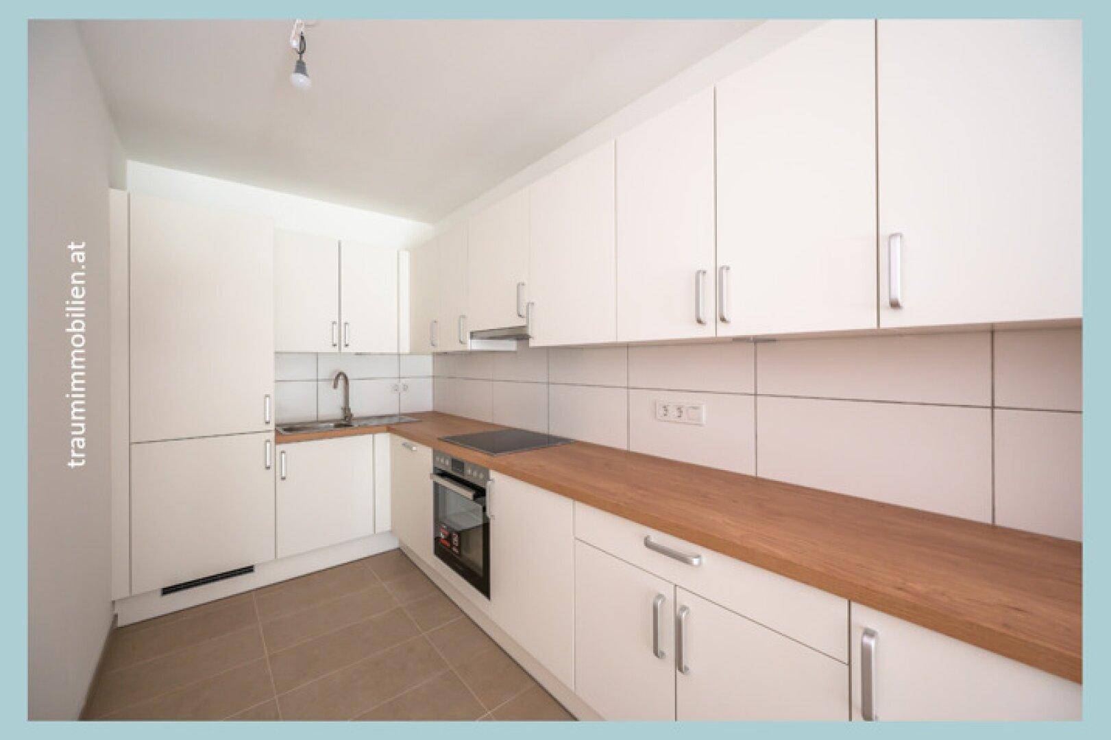 Moderne Einbauküche mit weißen Schränken, Holz-Arbeitsplatte und integrierten Geräten.