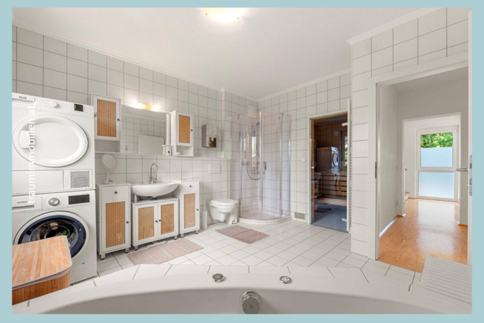 Geräumiges Badezimmer mit Waschmaschine, Trockner, Dusche, Badewanne und integrierter Sauna.