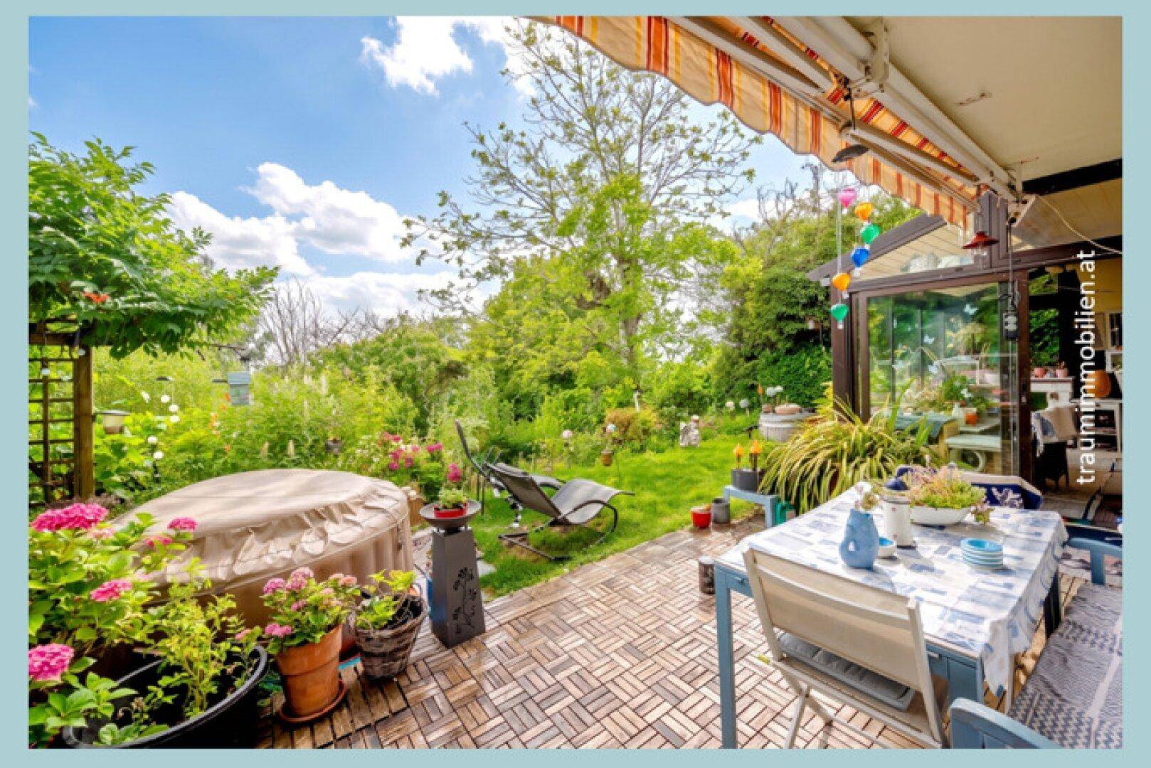 Eine großzügige, gepflasterte Terrasse mit Gartenmöbeln bietet viel Platz zum Entspannen im üppigen, sonnigen Garten.