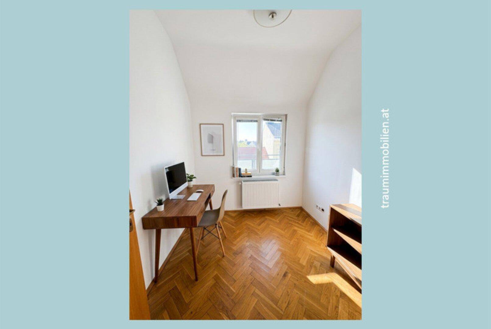 Kleines Arbeitszimmer mit Fischgrätparkett, Schreibtisch und Fenster für Tageslicht.