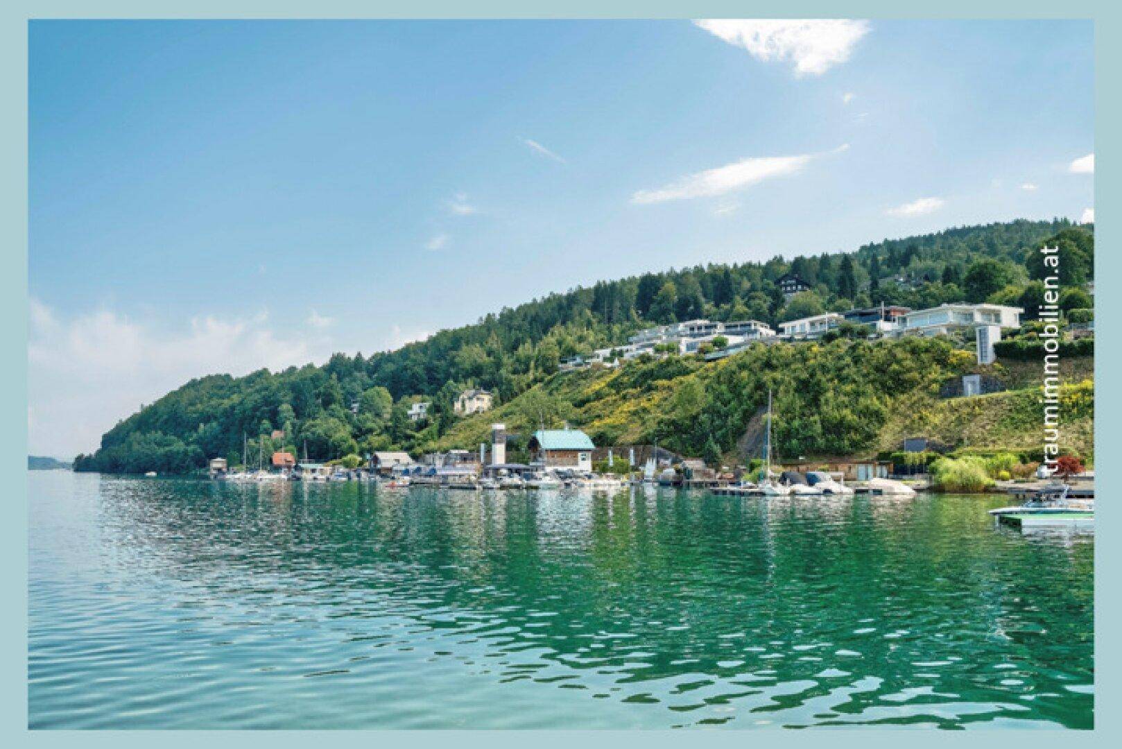 Malerischer Ausblick auf den Wörthersee mit luxuriösen Anwesen am bewaldeten Ufer.