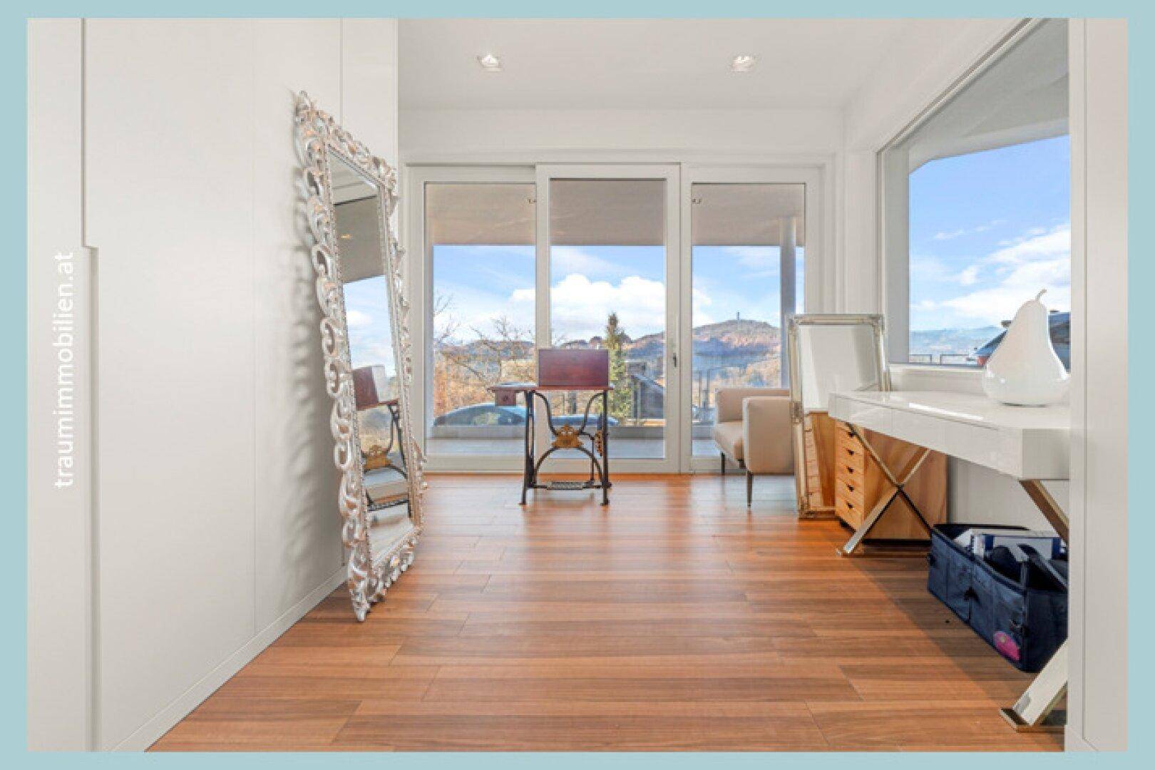 Heller Flur mit Holzboden, großem Spiegel und Zugang zu einem Balkon mit Weitblick.