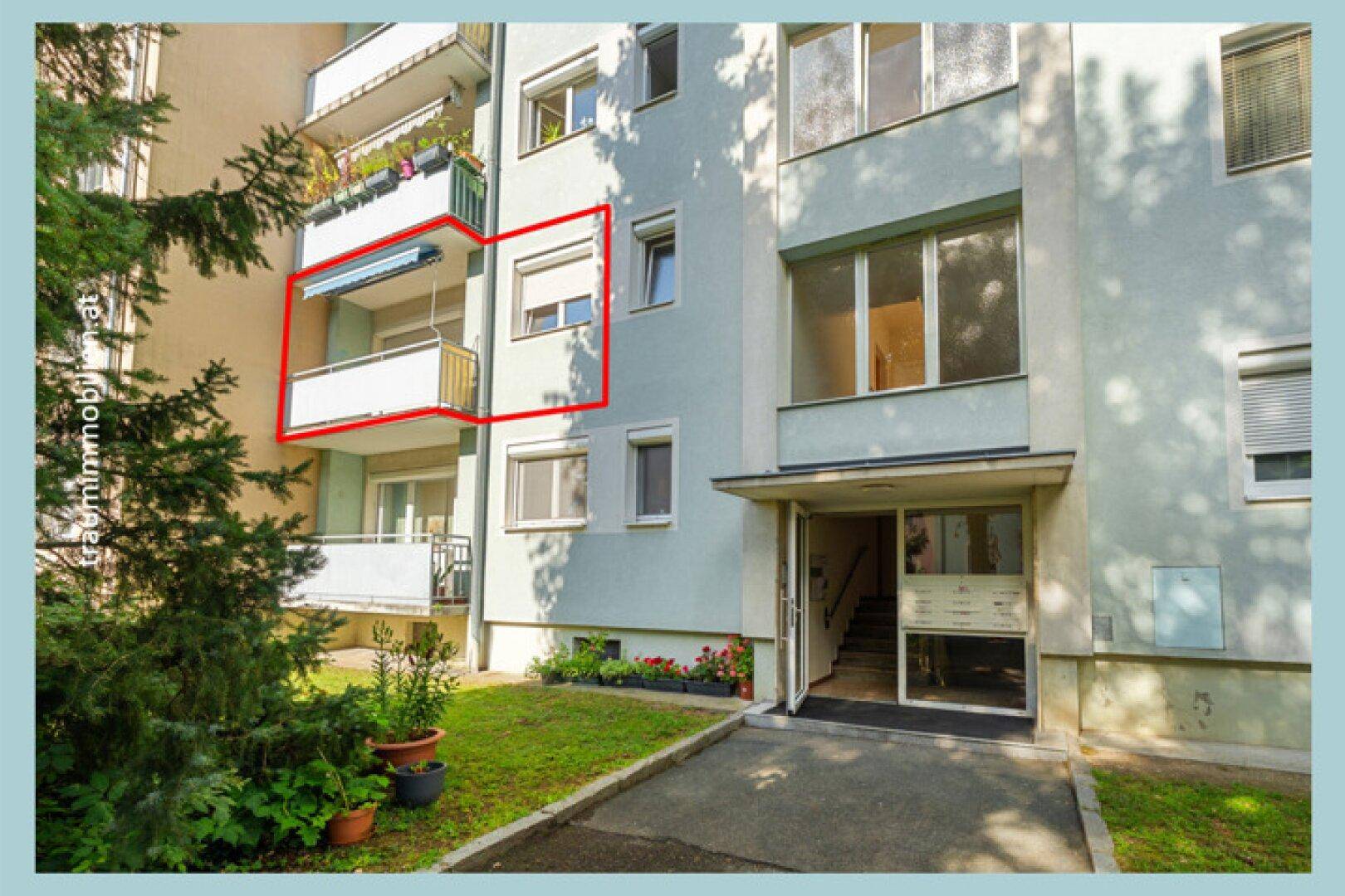 Eingangsbereich eines Mehrfamilienhauses mit Treppenaufgang und Balkon.