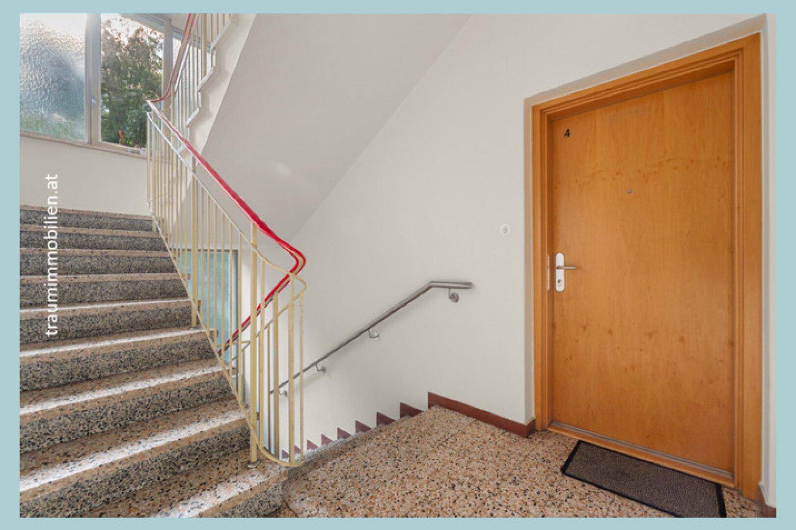 Helles Treppenhaus mit Terrazzoboden und Handläufen in einem Mehrfamilienhaus.