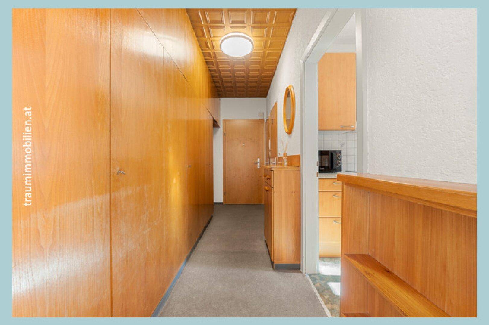 Langer Flur mit integrierten Holzschränken und gemusterter Deckenverkleidung.