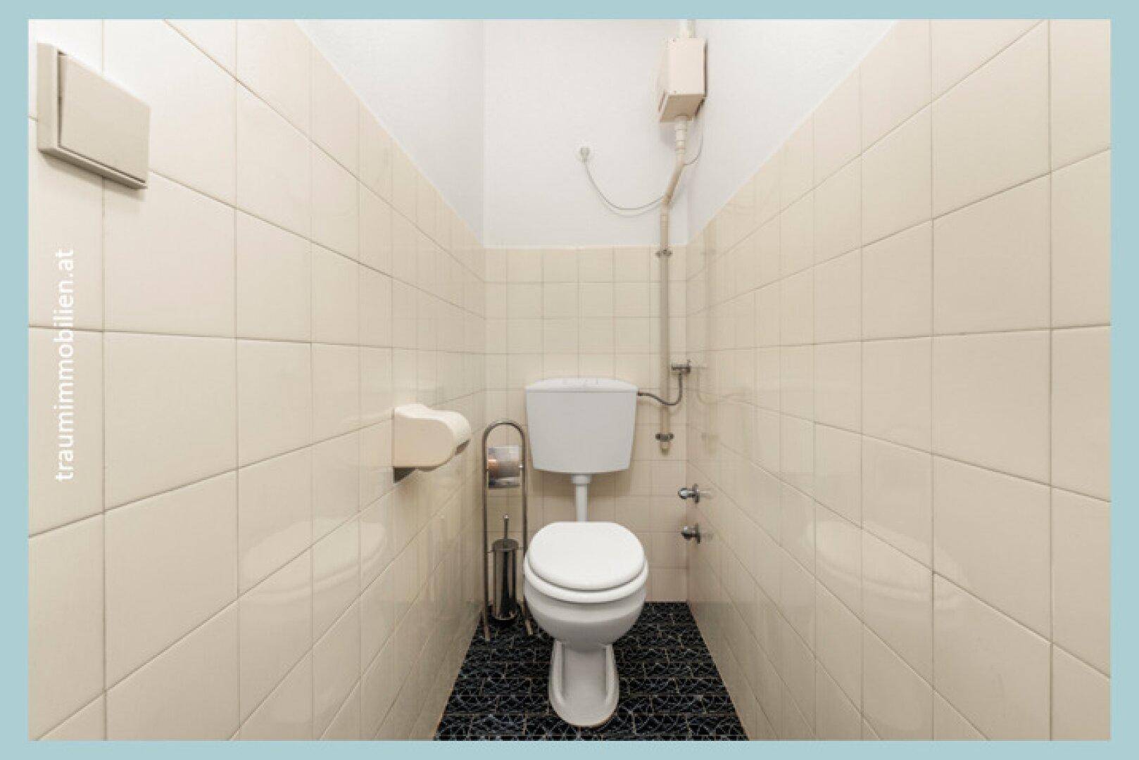 Separates WC mit hellen Fliesen, Toilette und Bidet, funktional eingerichtet.