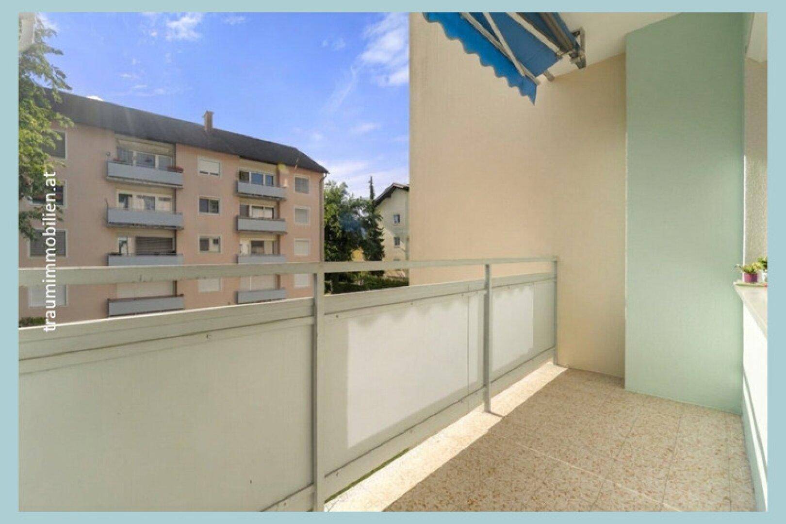 Geräumiger Balkon mit Fliesenboden und Blick auf die umliegenden Gebäude.